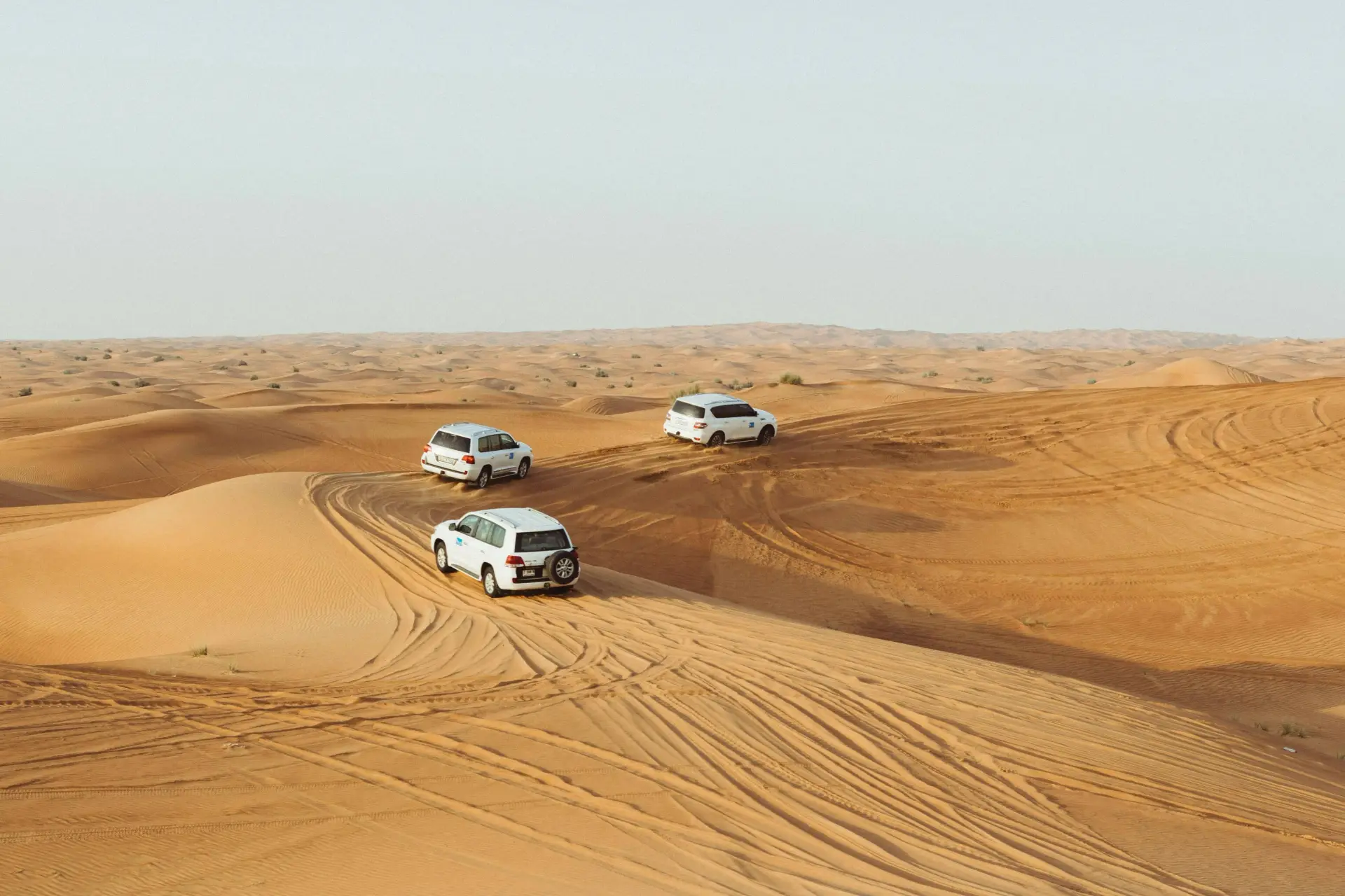 Luxury 4x4 desert safari convoy crossing red sand dunes outside Dubai